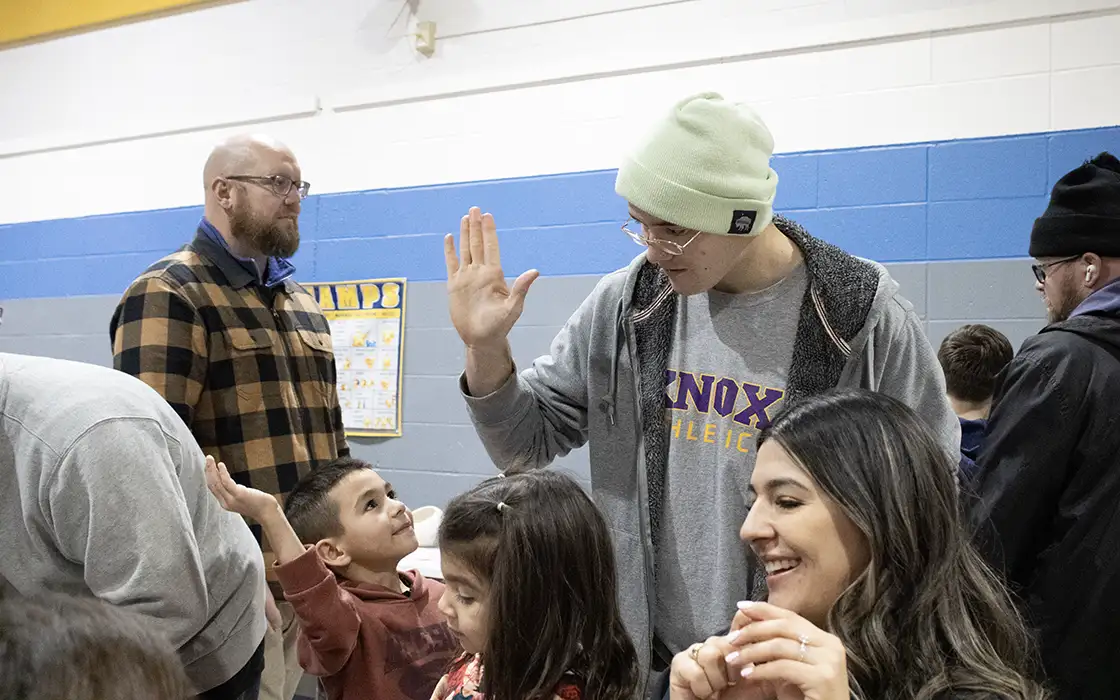 A student receives a high five from an elementary aged student in a school in the community.