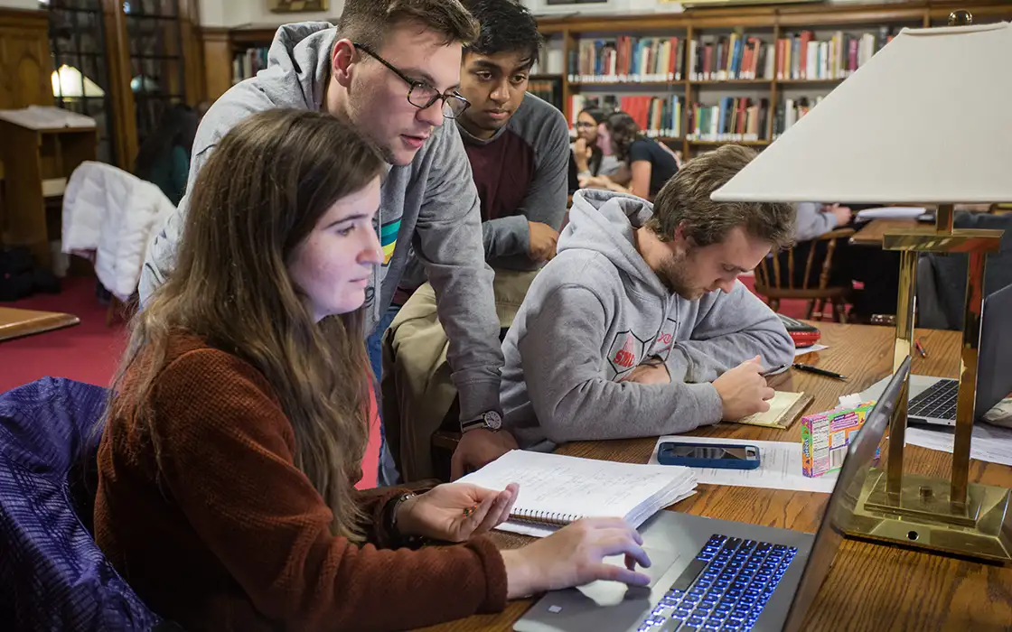 A group of students studying together looking at a laptop.