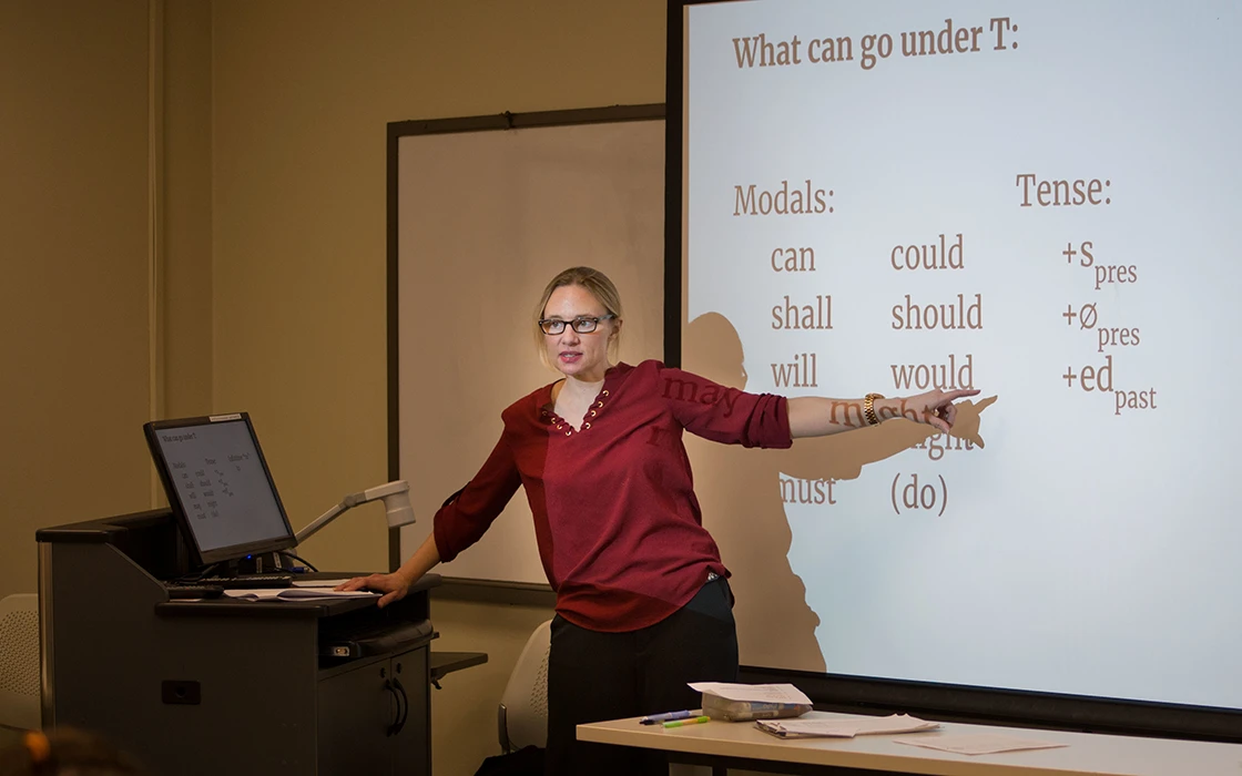 Professor Emily Anderson stands in front of a screen and speaks. 