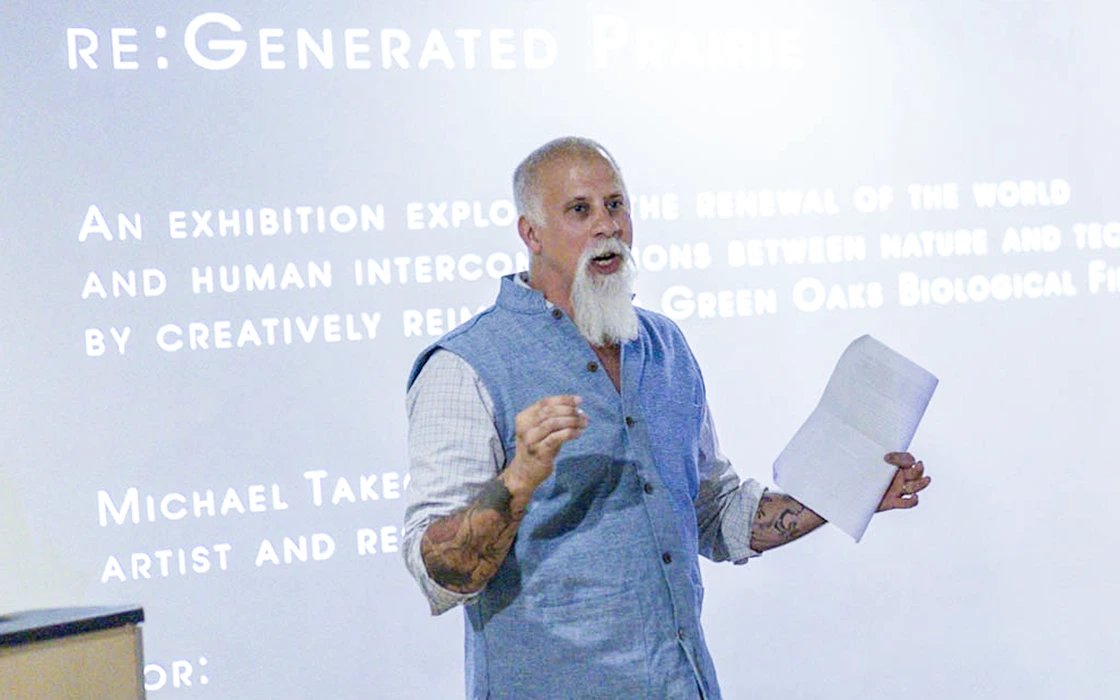 Religious Studies Professor Robert Geraci stands in front of a screen with text and speaks.