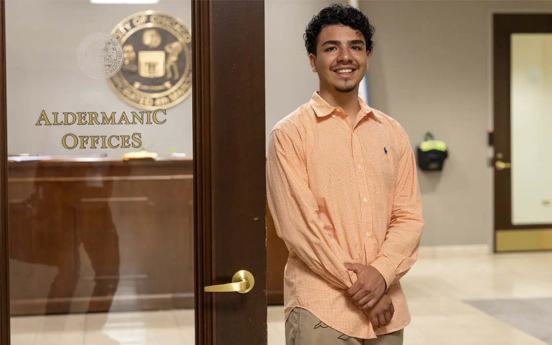 A student leans against the door frame of an alderman's office.