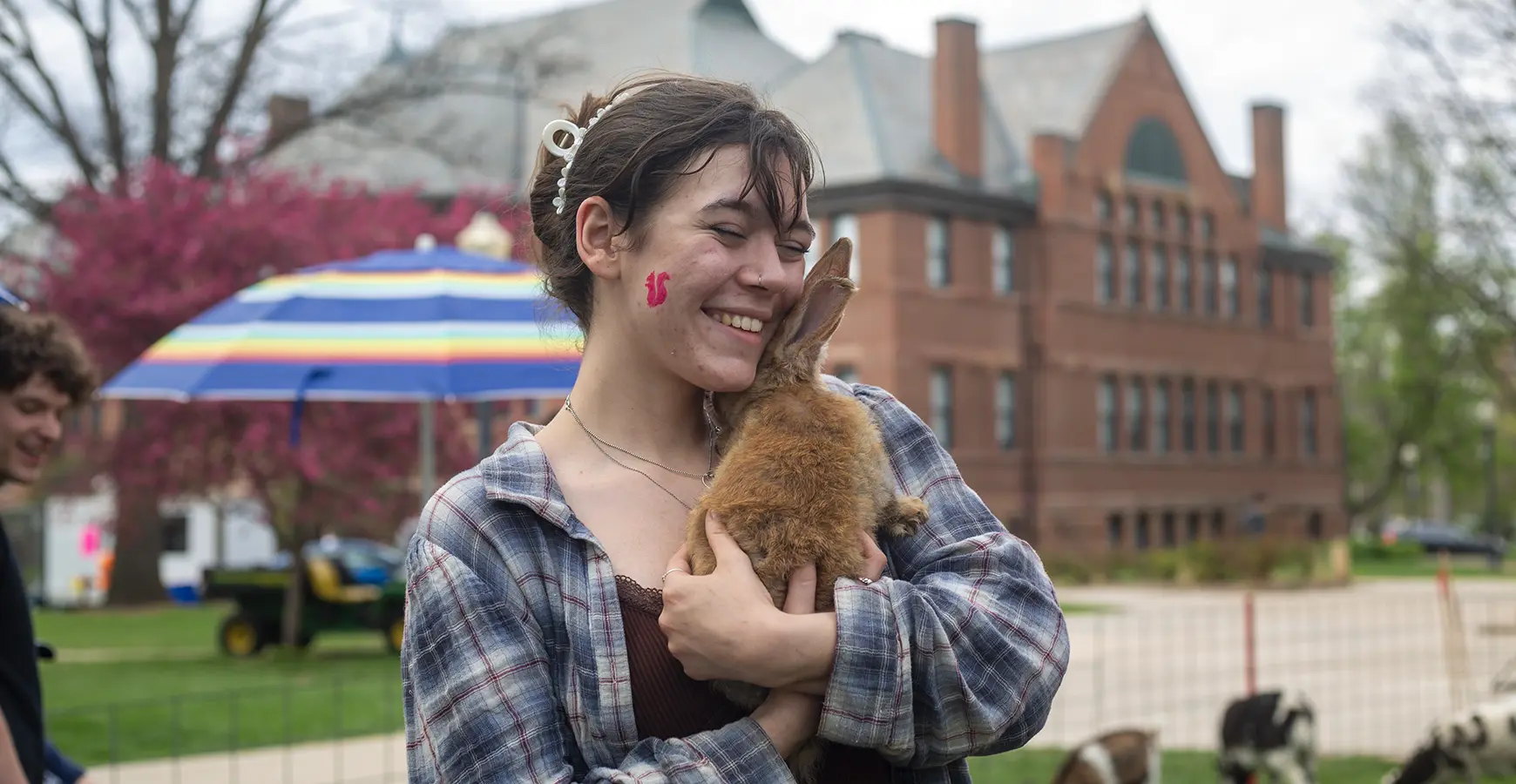 A student holds a rabbit at an outdoor event.