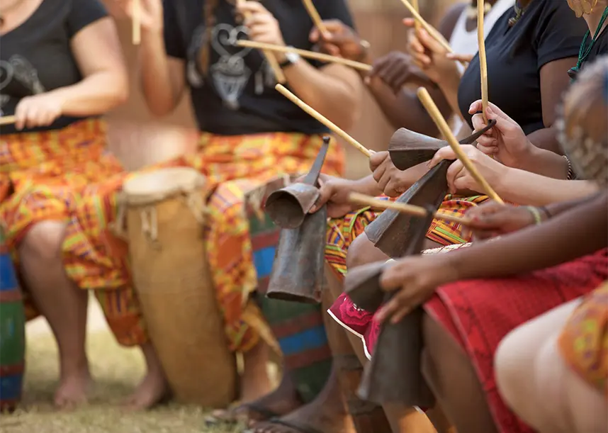 People sit in a line, playing drums.