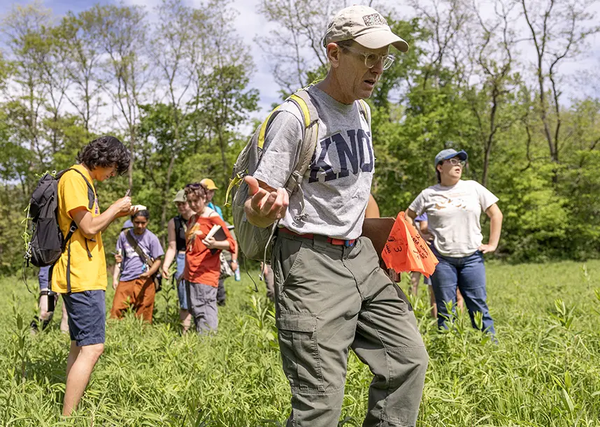 A professor and students walking through a field in Green Oaks.