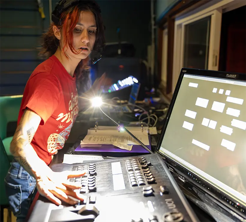A student working in a booth on technical equipment.