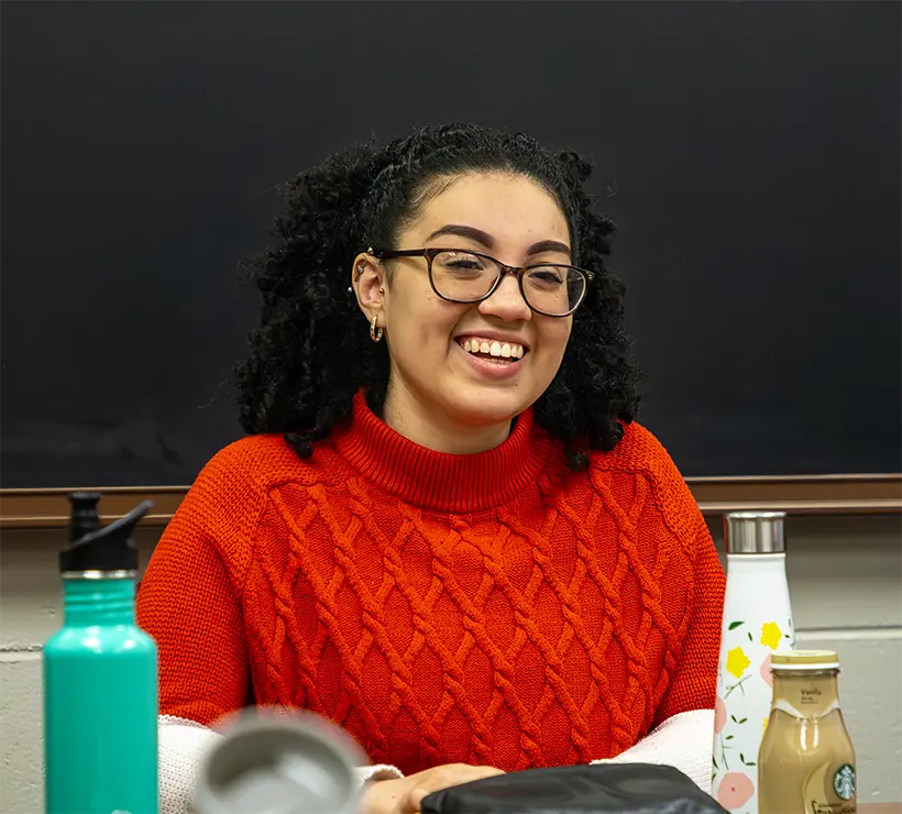 Dianell sitting in a classroom smiling.