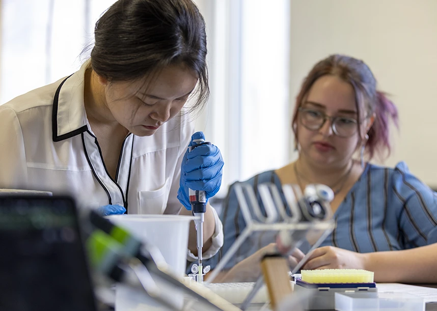 Two students work in a lab setting.