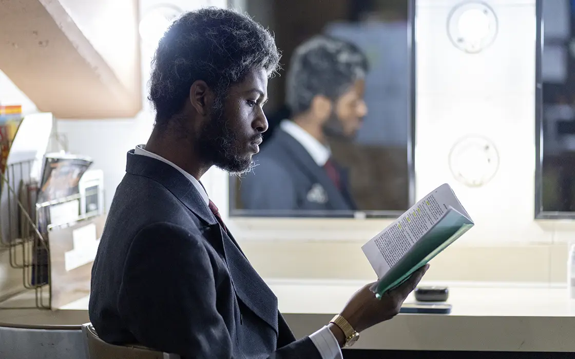 A student sits in front of a mirror with lights reading the script.