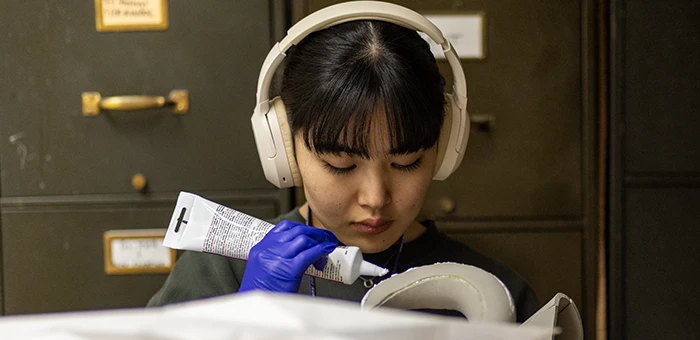 A student sits with headphones on while working on designing a costume.