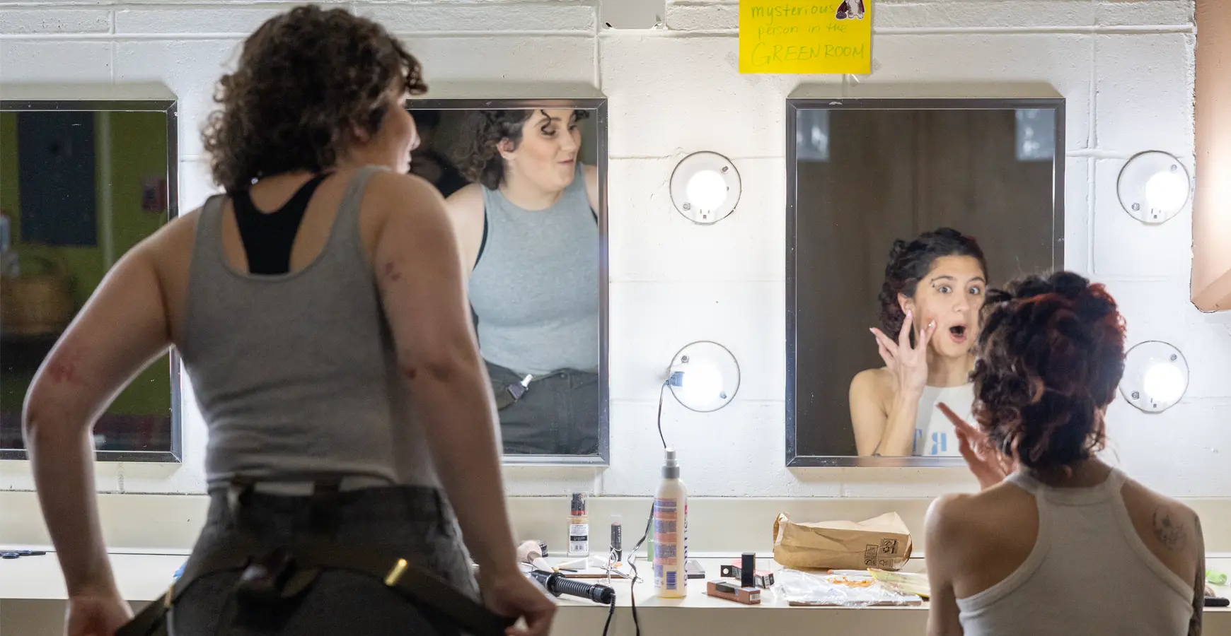 Two student stand in front of mirrors getting ready for the performance.