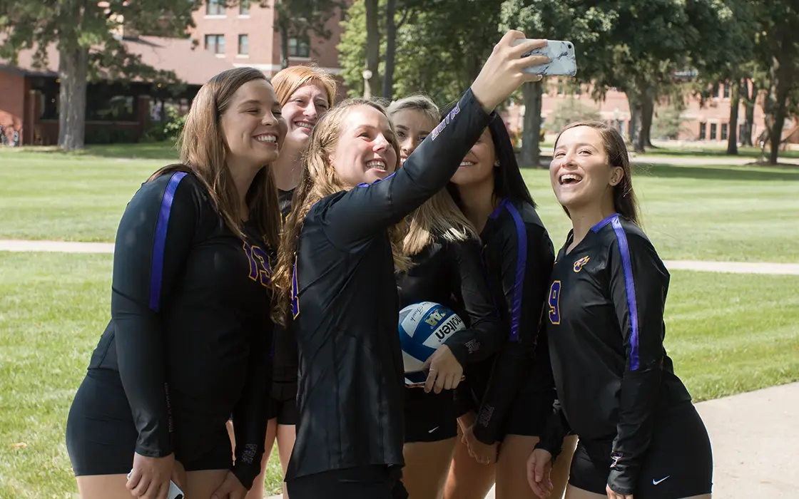 Four volleyball payers gather together for a selfie.