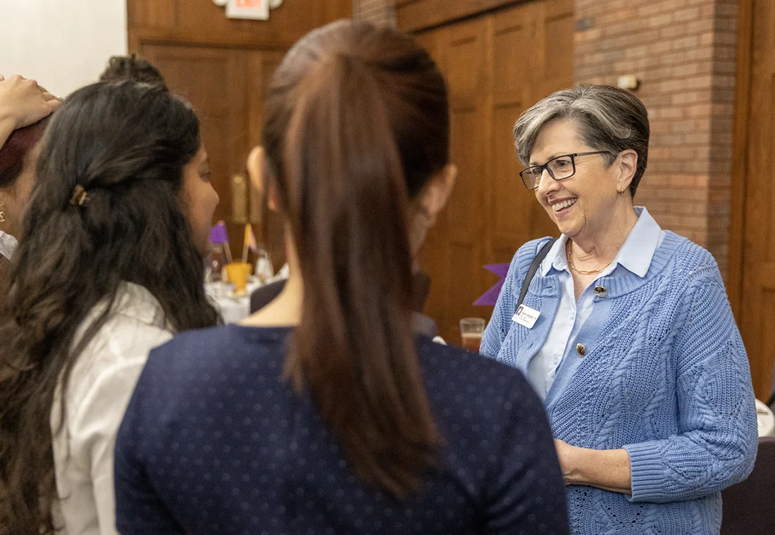 A member of the Knox College Alumni Council speaks with two students at a career networking event.