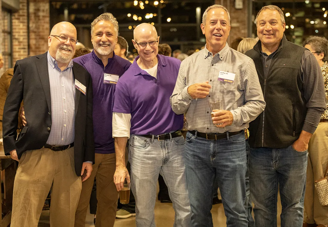 A group of five alumni pose for the camera during a Homecoming reception