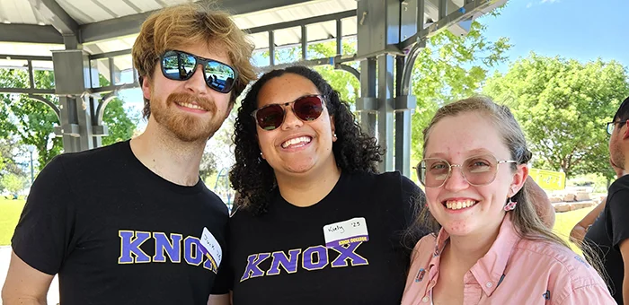 Three Knox alumni, each wearing sunglasses, smile and pose for the camera.