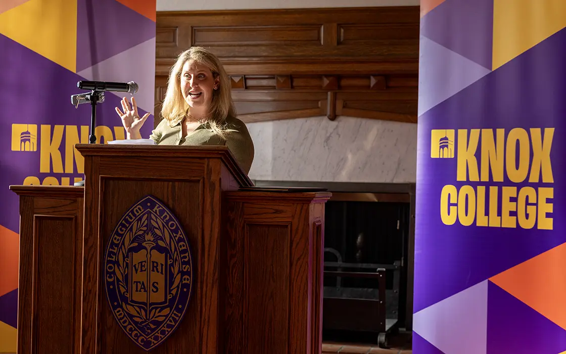 A Knox alumna stands at a podium during an award ceremony.