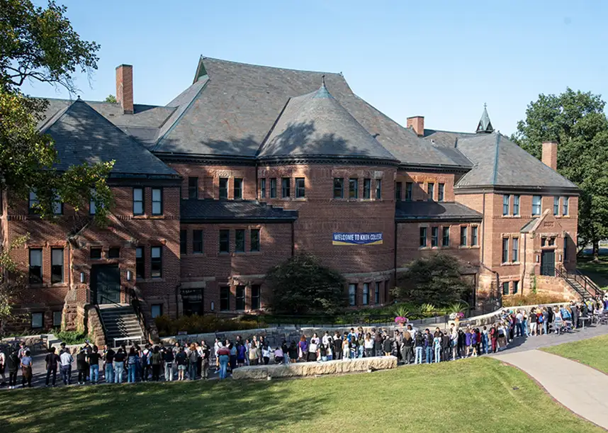 Knox students, faculty, and staff line the south side of Alumni Hall shaking each other's hands during the annual Pumphandle. A banner on Alumni Hall says "'Welcome to Knox."
