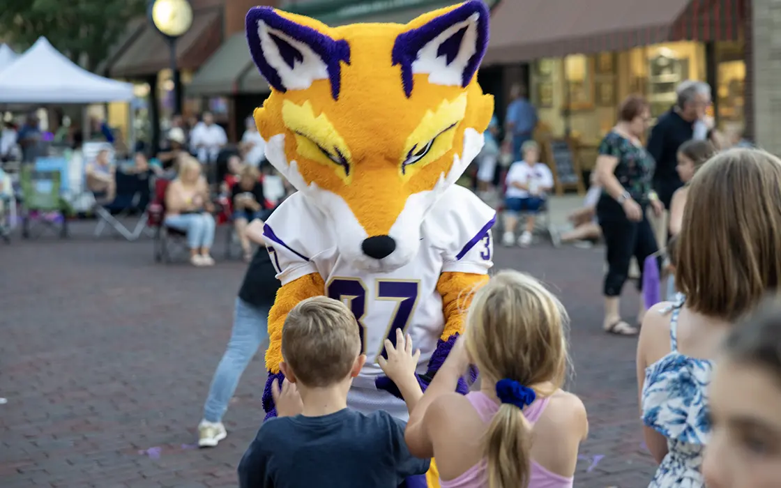 Blaze the Fox mascot gives high fives to two children at an event downtown.