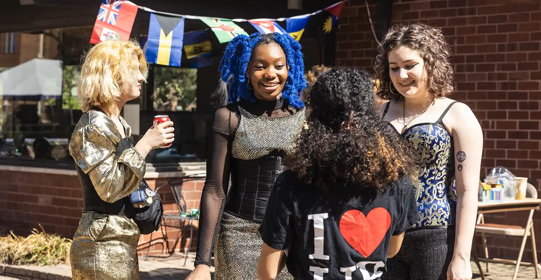 A group of students stand outside talking and smiling.