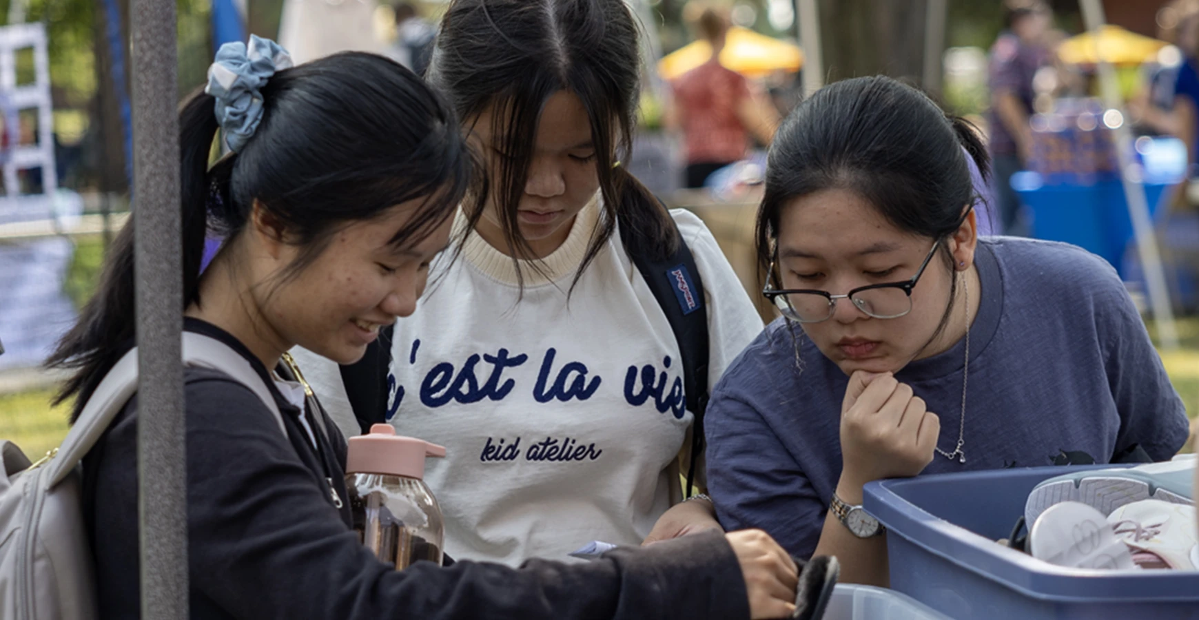 Three students look at a bin of shoes.