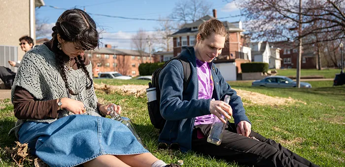 Knox students sitting on a lawn building terrariums.