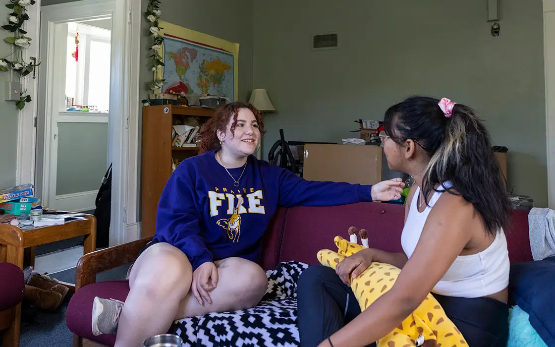 Two students talking to each other on a couch in Post Hall.