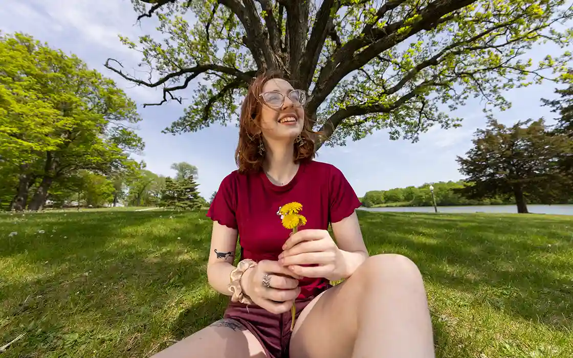 A student sits below a tree on the Knox campus.