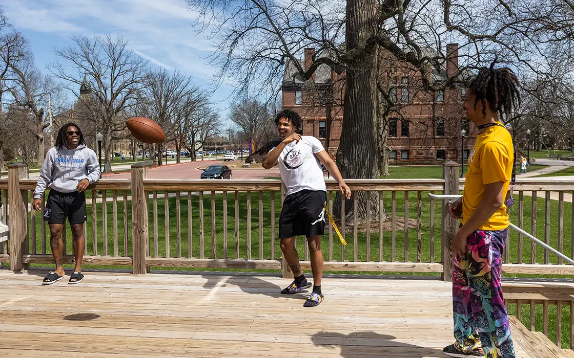 Members of Tau Kappa Epsilon fraternity play football on their house deck.