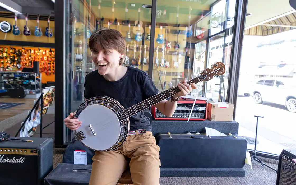 A Knox Student plays a banjo in a local music shop.
