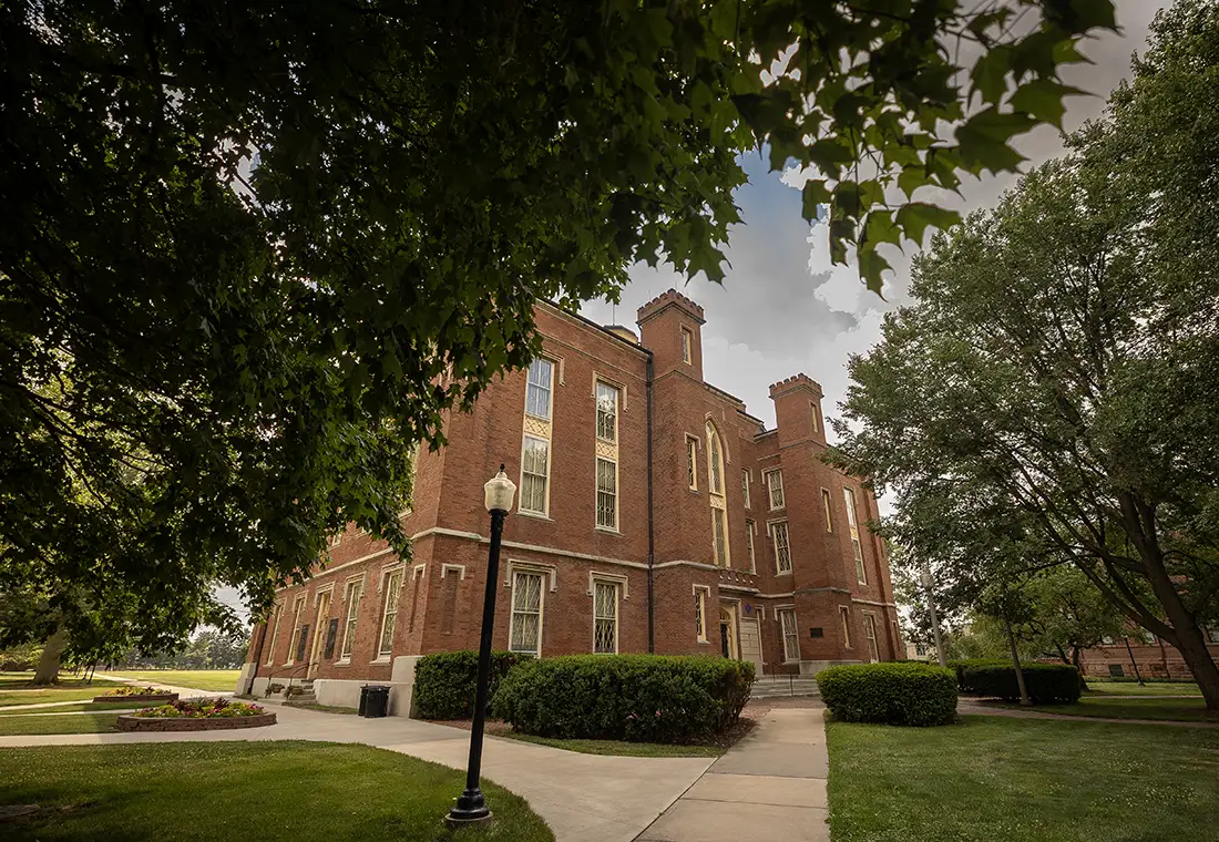 Image of Old Main, shot from under a canopy of trees. 