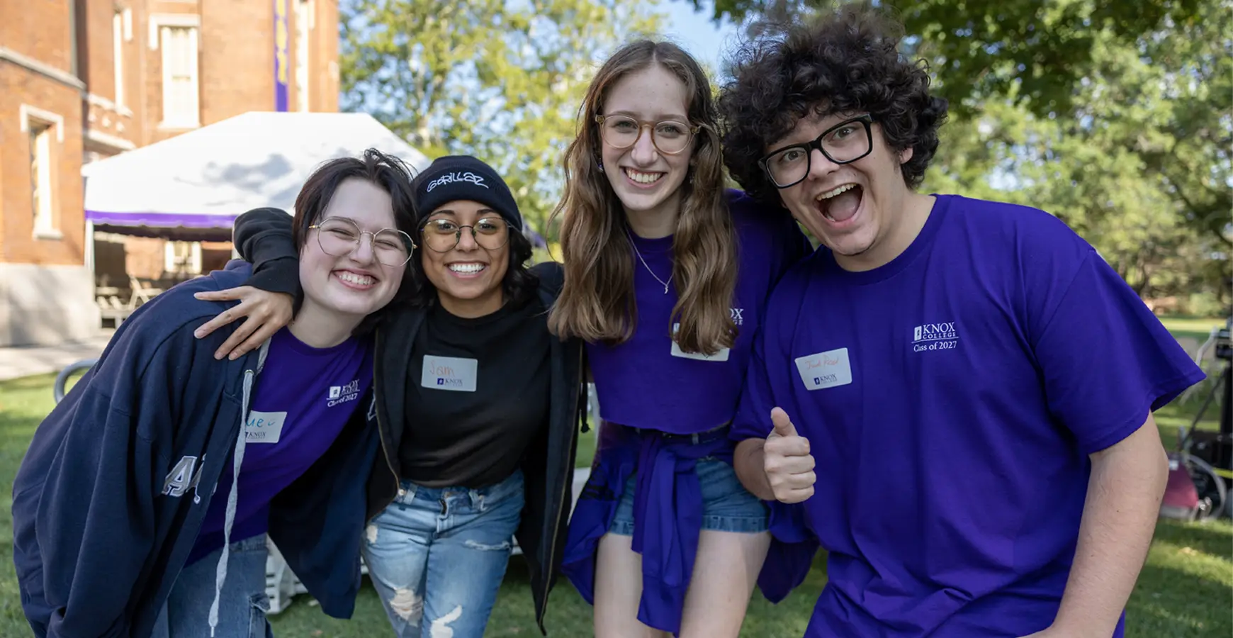 A group of students with their arms around each other, smiles for the camera.