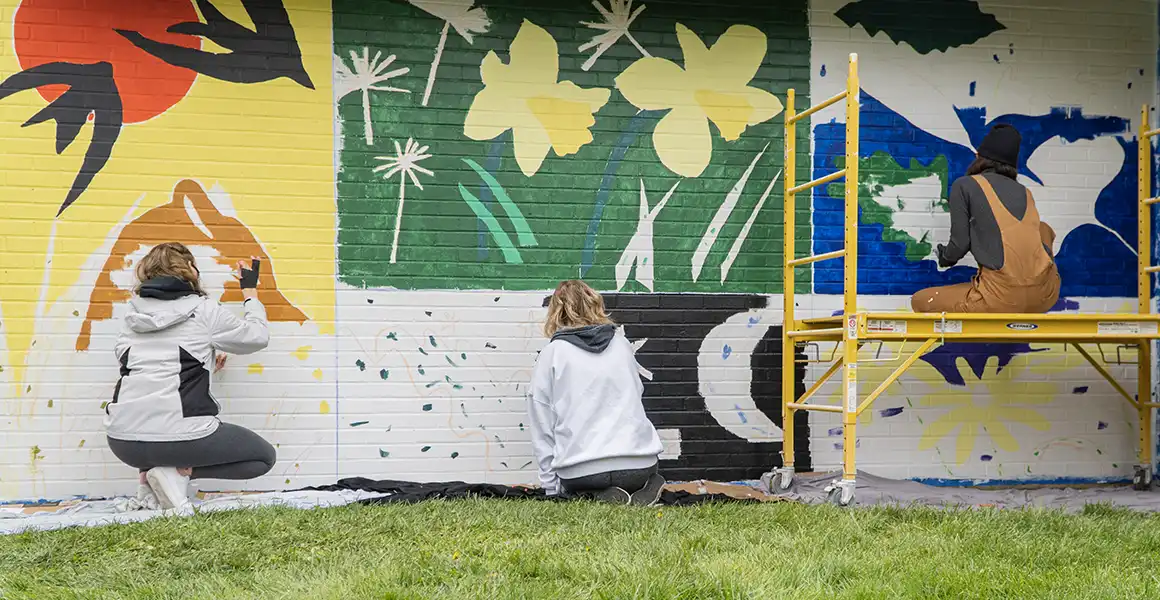 Two students painting a mural. 
