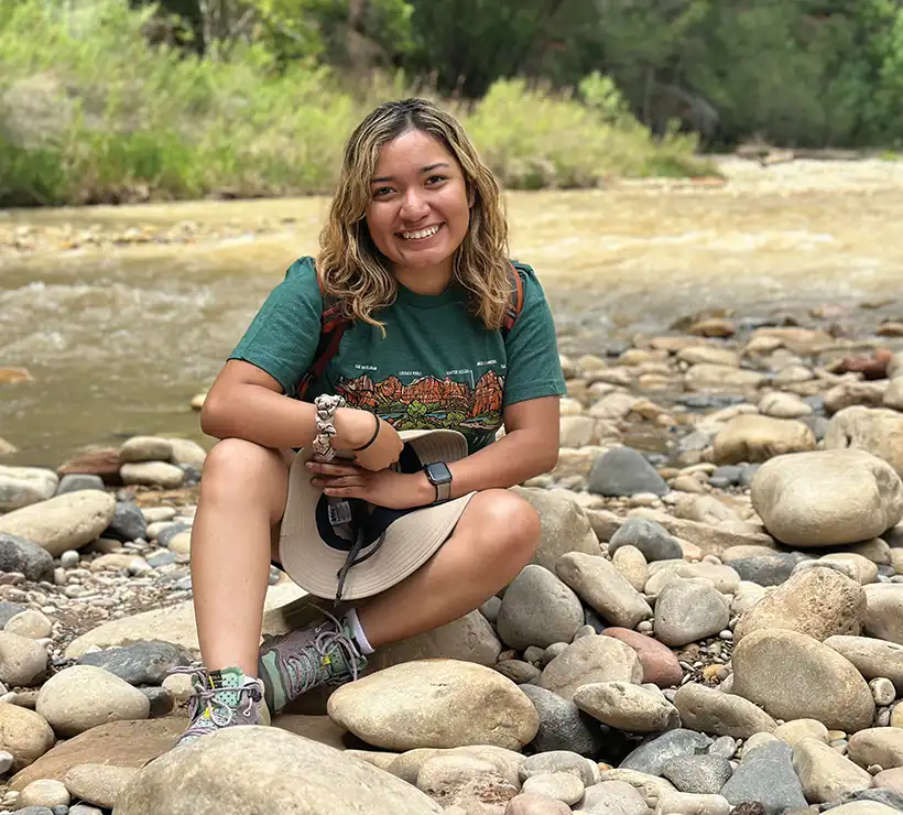 Karen kneeling down in a riverbed over rocks.