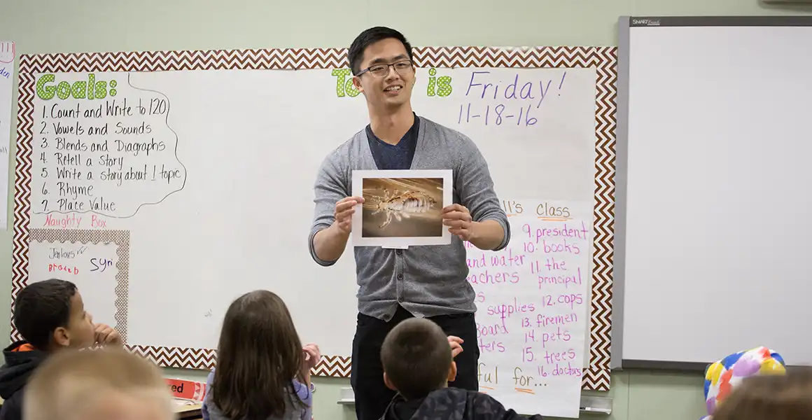 A Knox student at the front of a classroom full of young students.