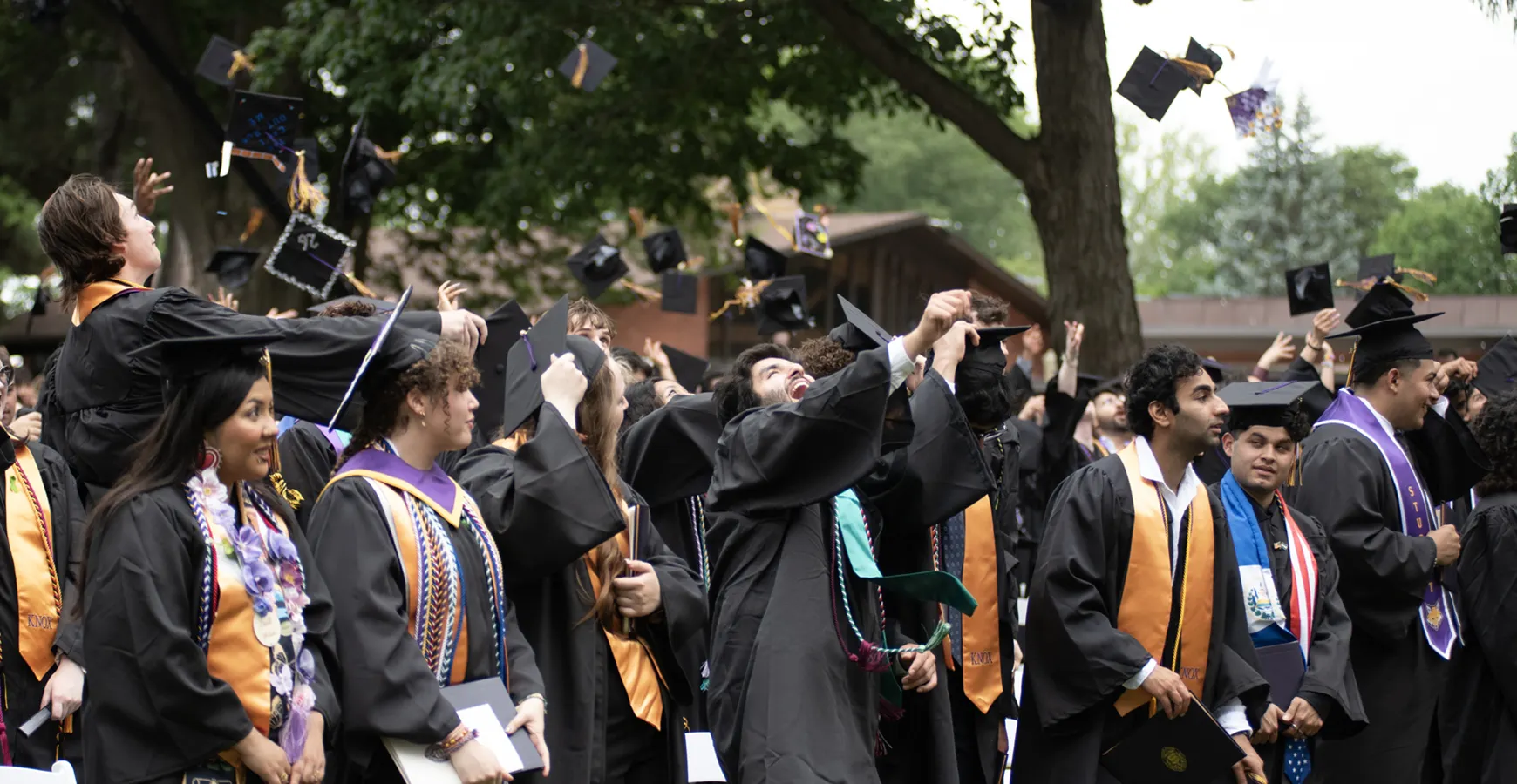 Graduates toss their graduation caps into the air joyfully. 