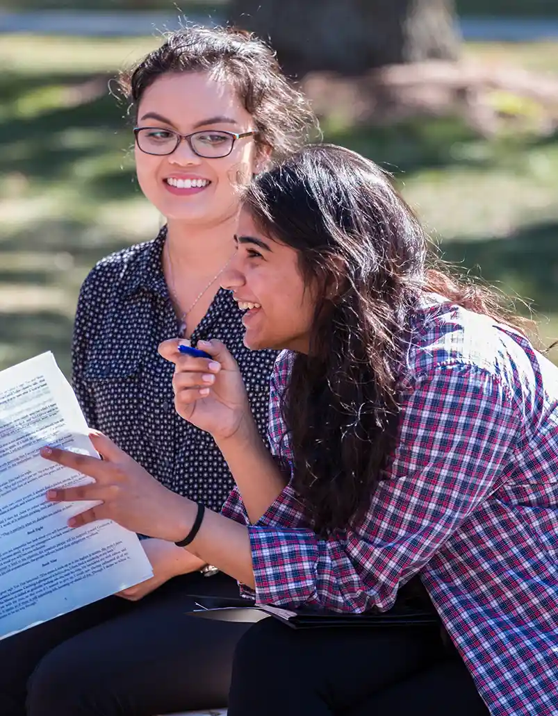 Two students sit outside, participating in a discussion during a Philosophy class.