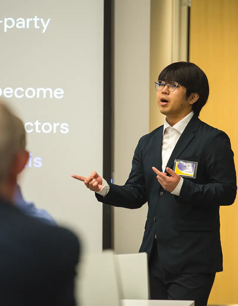 Dressed in a suit, a student gives a presentation to his business class.