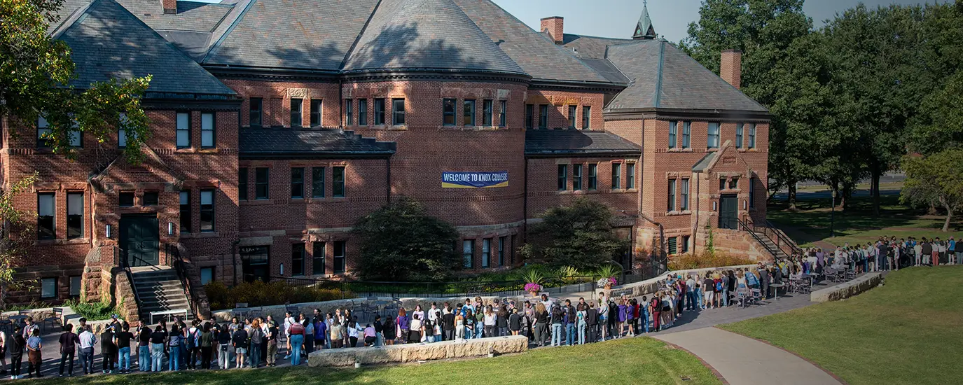 Knox faculty, staff, and students shake hands in a line on the Alumni Hall patio.