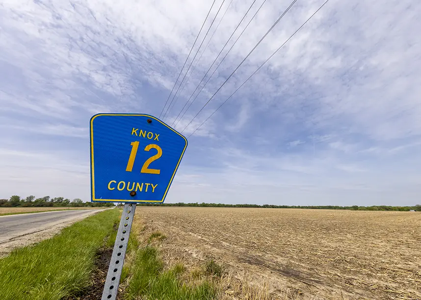 A County Highway 12  road sign in front of a field and big sky.