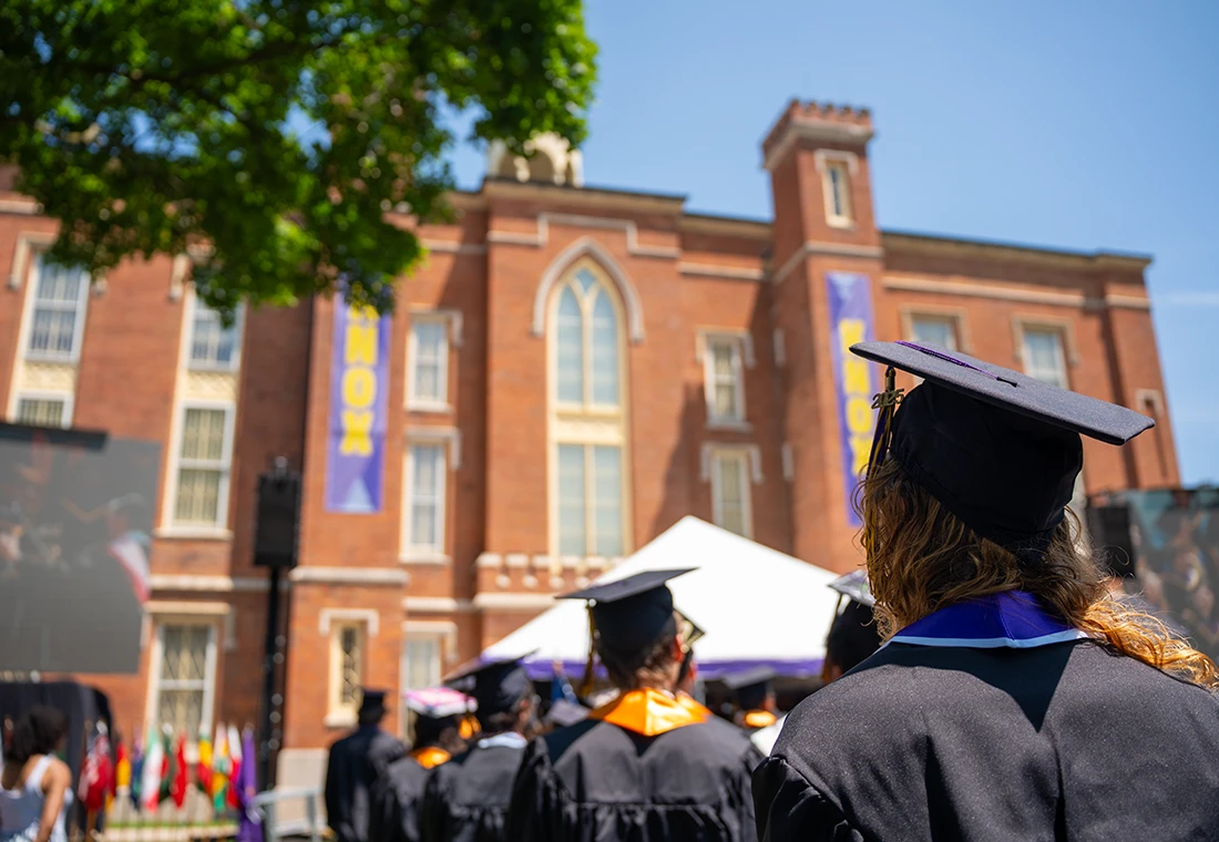 Knox graduates face the stage and Old Main during their Commencement ceremony.