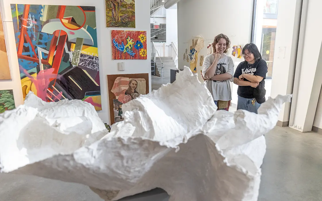 Two Knox students look at a white, organically shaped sculpture in an art studio in the Whitcomb Art Center.