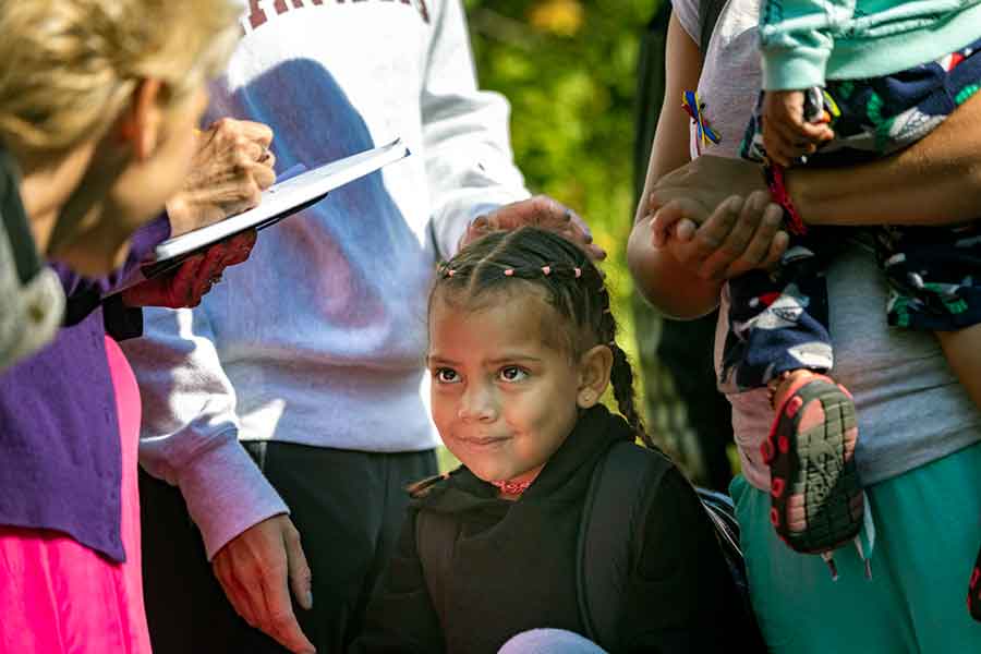 A young Venezuelan girl smiles as a volunteer says goodbye before boarding a bus to leave Edgartown and take them to the mainland. (Jesse Costa/WBUR)