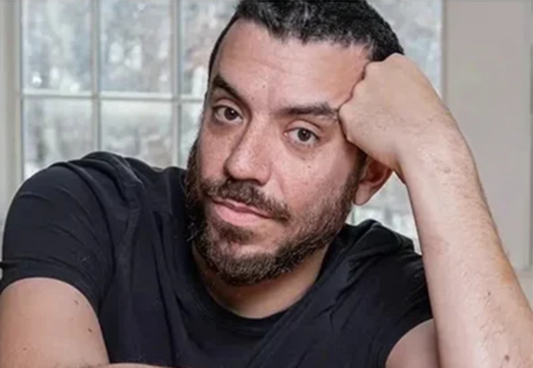 Kaveh Akbar looks at the camera, leaning to the side with his temple on his closed fist.