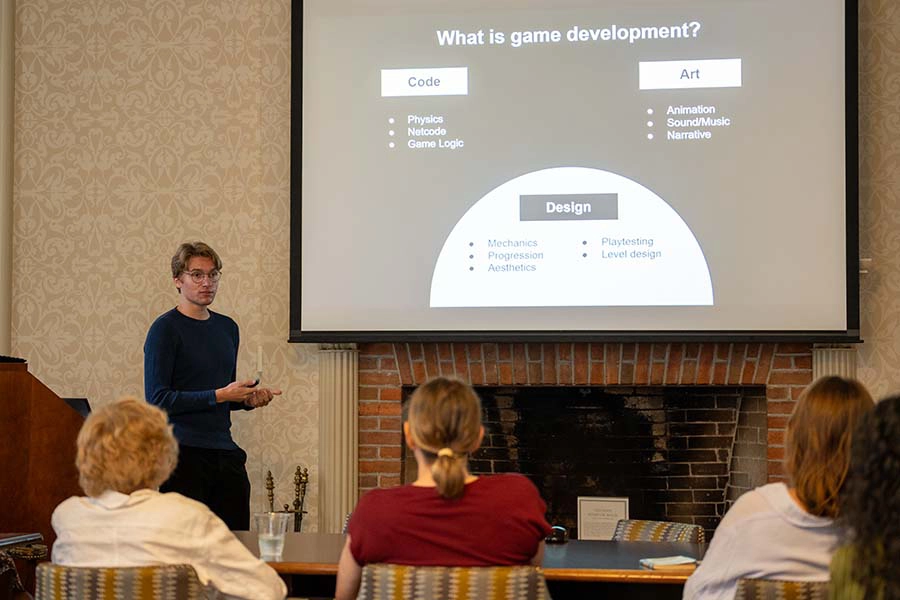 A Knox student stands at the front of the room by a podium presenting their summer research project. 