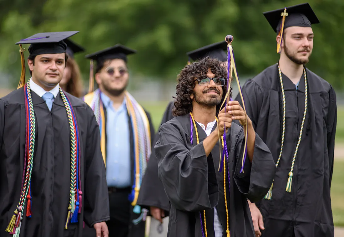 A student marshal leads graduates into the Commencement ceremony.
