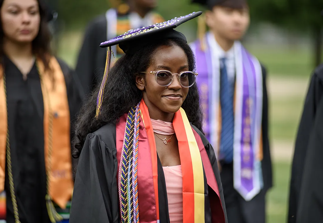 A graduate smiles slightly in the Commencement ceremony. 