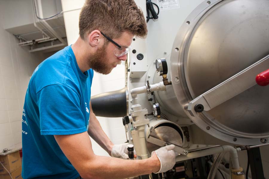 Knox College student Alex Volkov loads nitrogen-filled glove box for chemistry research.