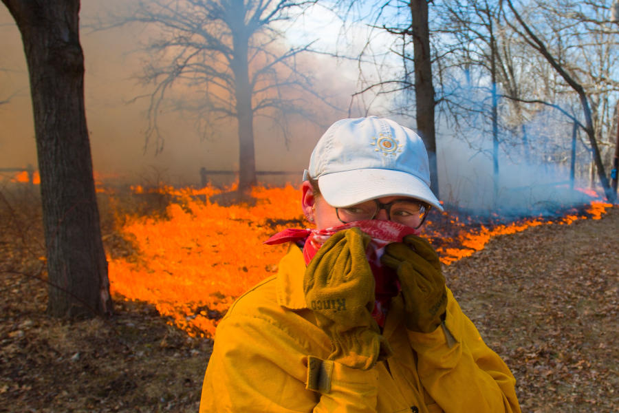 Knox College student turns away from the heat during the annual Prairie Burn at Green Oaks.
