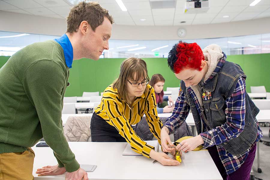Ben Farrer observes as students in his winter 2020 course, Environment and Apocalypse, as they practice suturing wounds on a banana.