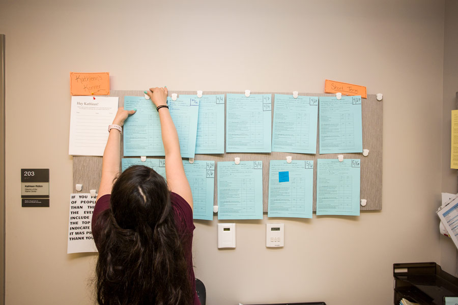 Student in Kleine Center for Community Service, posting volunteer service opportunities on bulletin board; 2017.