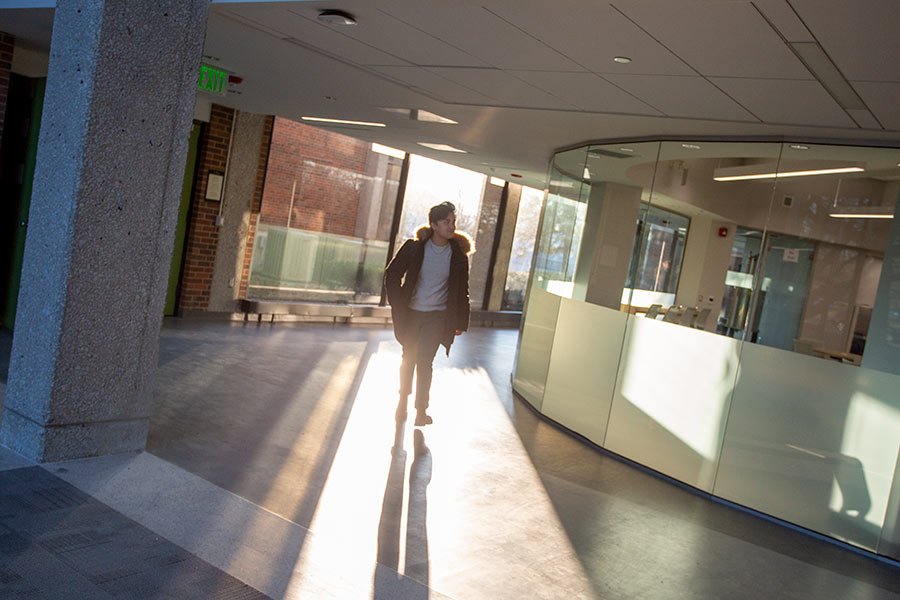 A lone student walks past the Amott Learning Commons in SMC as sunlight streams in behind him.